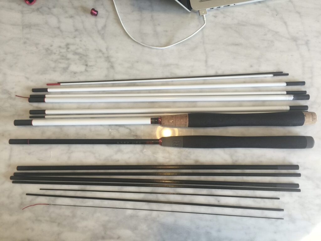 Snow Tanuki 425 tenkara rod prototype laid out on a workbench, showing white and black rod sections and grip components during early development.